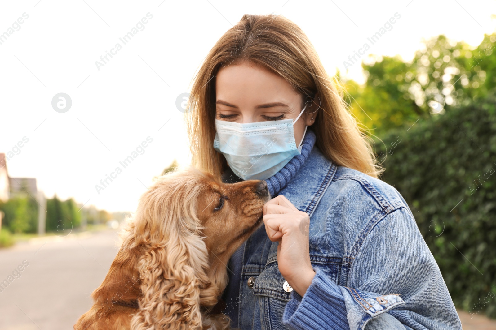 Photo of Woman in protective mask with English Cocker Spaniel outdoors. Walking dog during COVID-19 pandemic