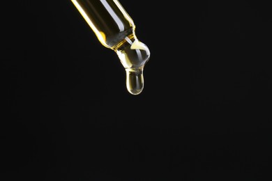 Photo of Dripping tincture from pipette on black background, closeup. Space for text