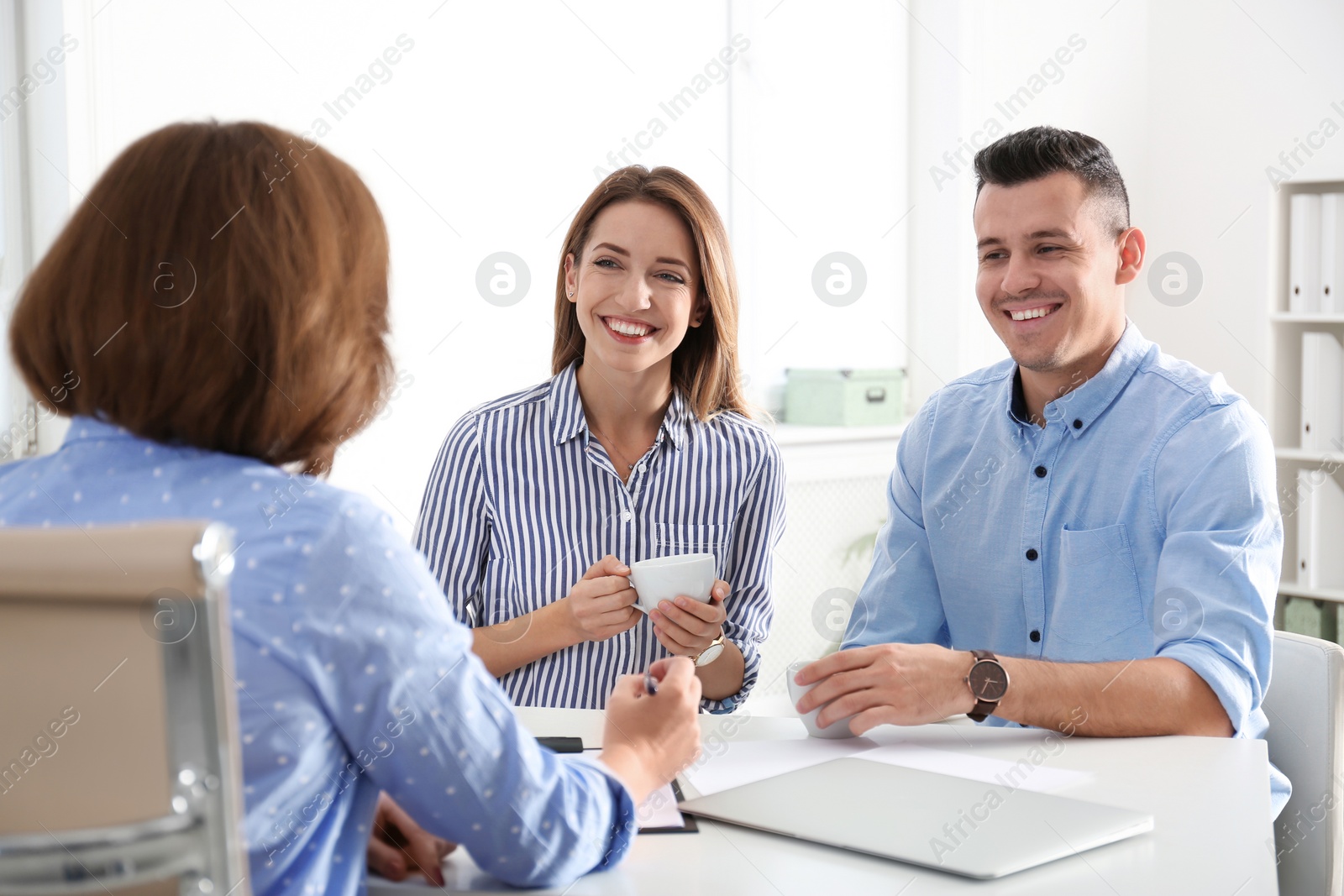 Photo of Real estate agent consulting young couple in office