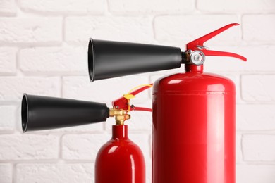 Photo of Fire extinguishers against white brick wall, closeup