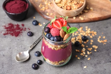 Photo of Delicious acai dessert with granola and berries served on grey table