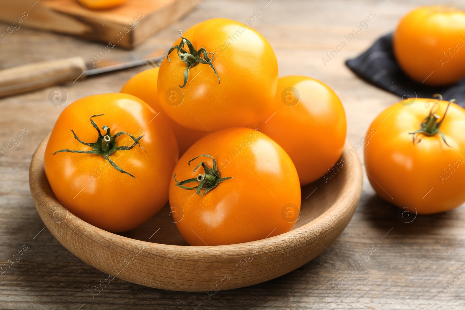 Photo of Many ripe yellow tomatoes on wooden table