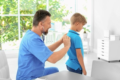 Male medical assistant examining child in clinic