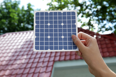Woman holding solar panel near building outdoors, closeup