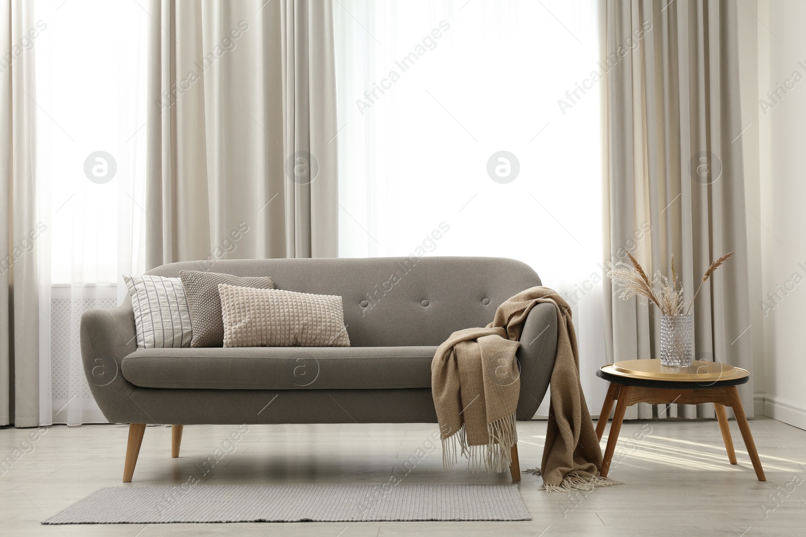 Photo of Grey sofa with pillows near window in stylish living room interior