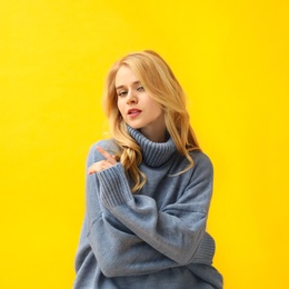 Photo of Beautiful young woman wearing warm blue sweater on yellow background