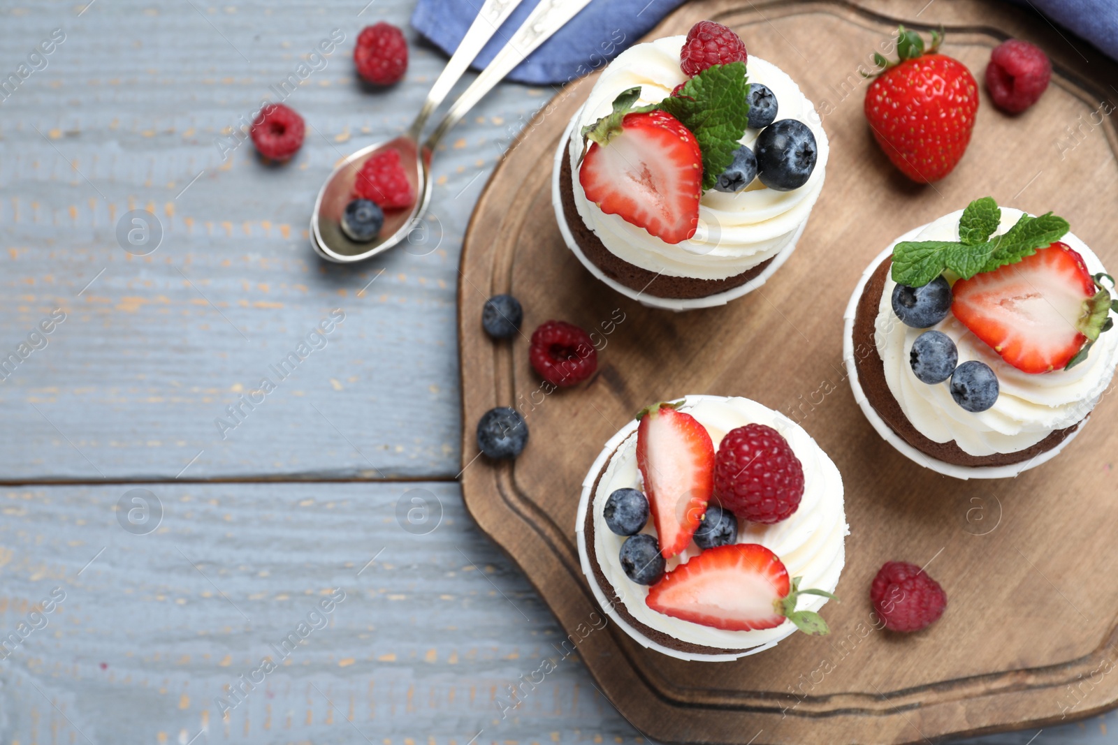 Photo of Sweet cupcakes with fresh berries on wooden table, flat lay. Space for text