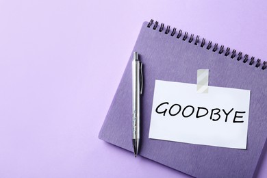 Note with word Goodbye, notebook and pen on violet background, space for text