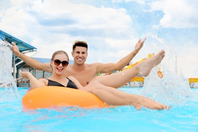 Photo of Happy couple with inflatable ring in swimming pool at water park