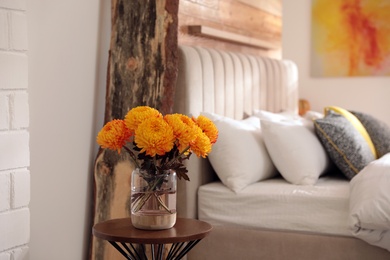 Photo of Beautiful autumn flowers on table in cozy bedroom interior. Space for text