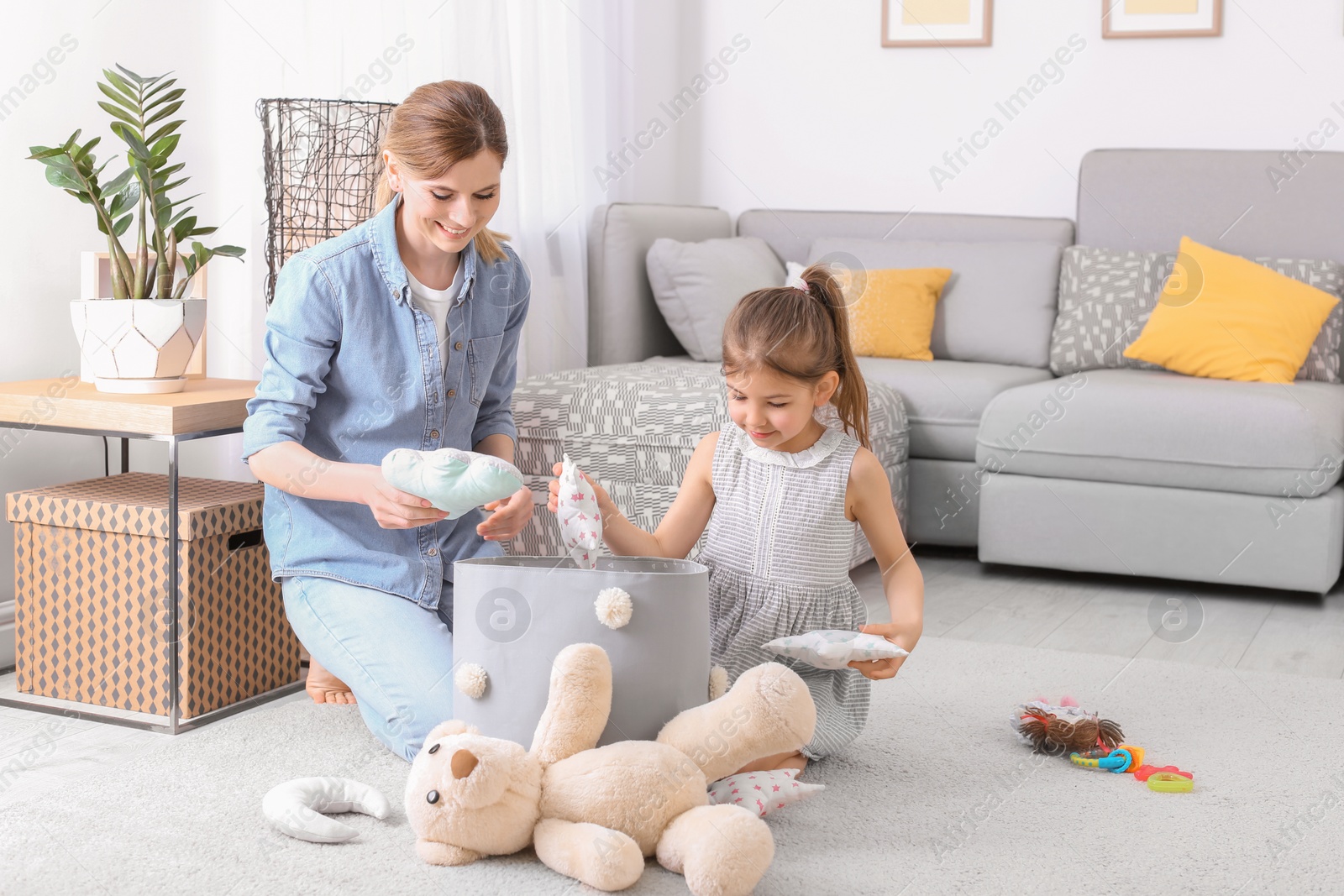 Photo of Housewife and daughter picking up toys after playing at home