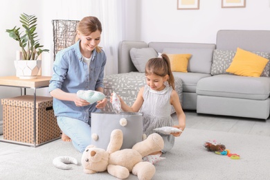 Housewife and daughter picking up toys after playing at home