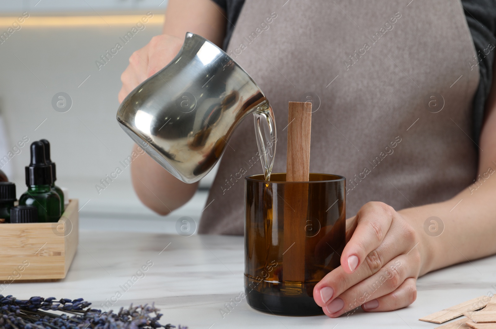 Photo of Woman making homemade candle at table in kitchen, closeup