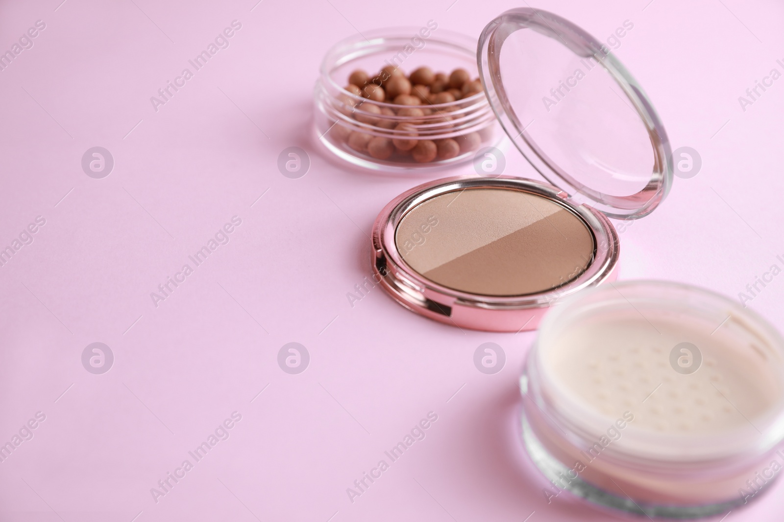 Photo of Different face powders on pink background, space for text