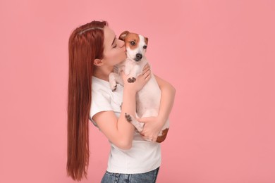 Photo of Woman kissing her cute Jack Russell Terrier dog on pink background. Space for text