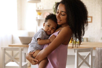 Photo of African-American woman with her baby in kitchen. Happiness of motherhood