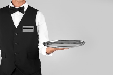 Photo of Waiter holding metal tray on grey background