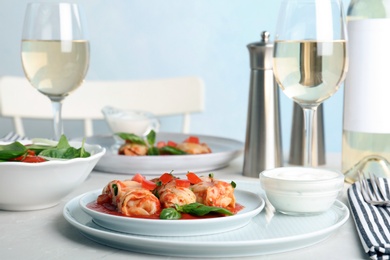 Photo of Plate with stuffed cabbage leaves in tomato sauce on table