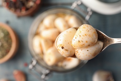 Photo of Preserved garlic in spoon over table, closeup. Space for text