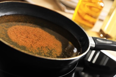 Photo of Frying pan with used cooking oil on stove, closeup