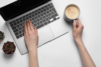 Woman using laptop at white table, top view