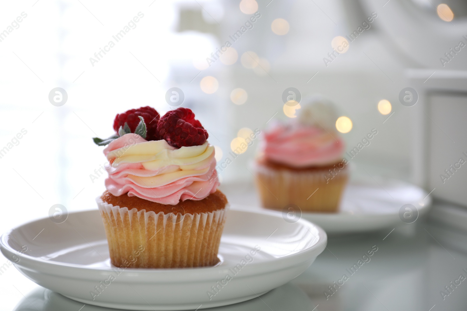 Photo of Delicious cupcake with raspberries on table against blurred lights, closeup. Bokeh effect