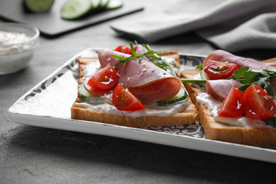 Photo of Tasty sandwiches with ham served on grey table, closeup