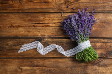 Photo of Beautiful fresh lavender bouquet with lace ribbon on wooden background, top view