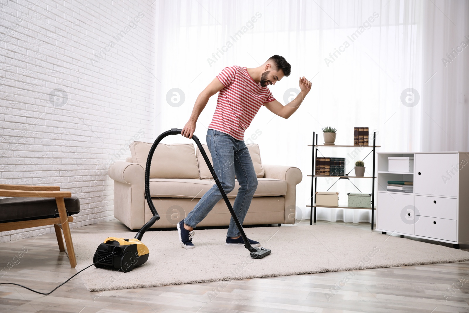 Photo of Young man using vacuum cleaner at home