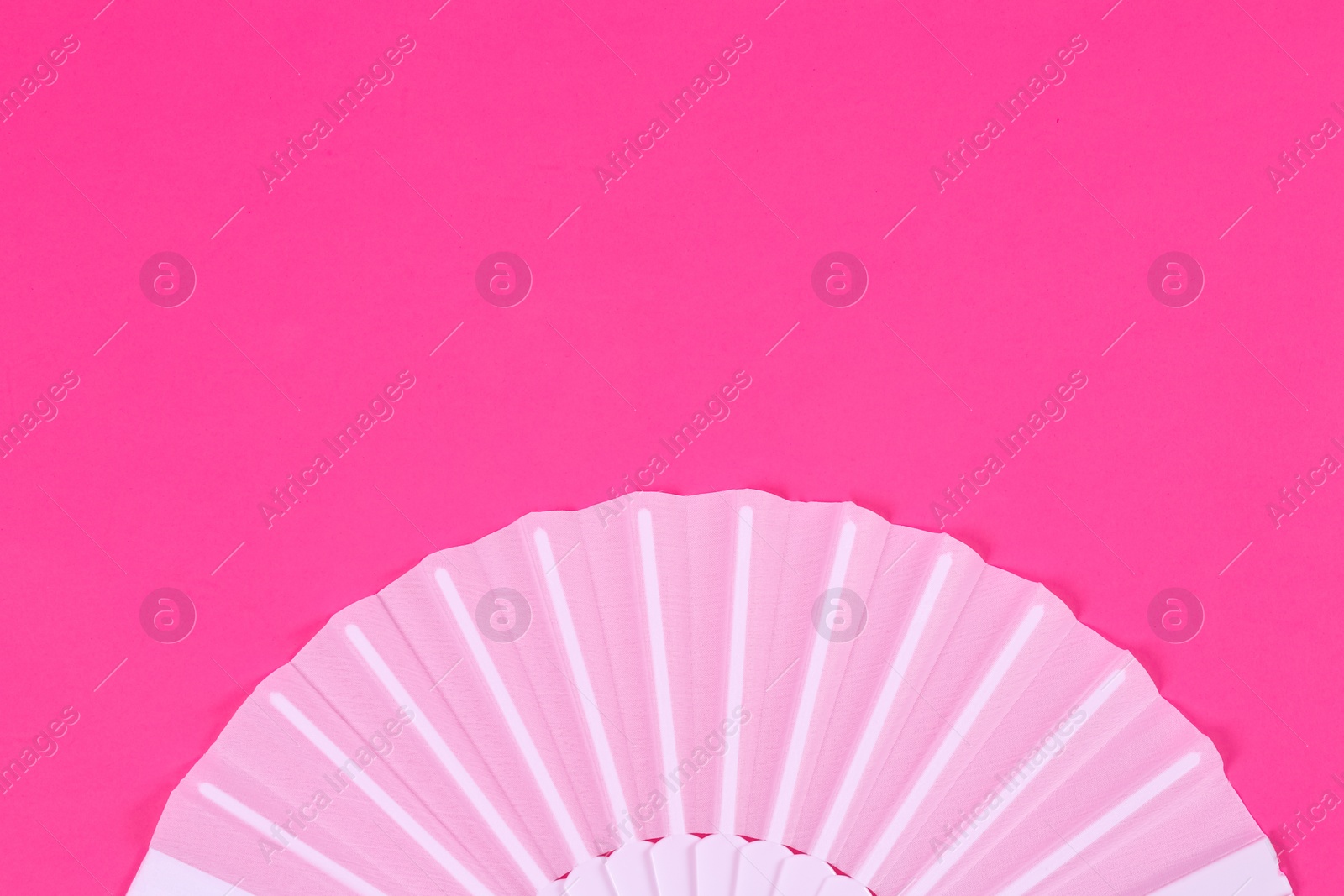 Photo of White hand fan on pink background, top view. Space for text