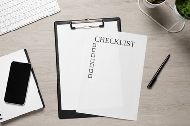 Clipboard with inscription Checklist, smartphone, plants and computer keyboard on white wooden table, flat lay