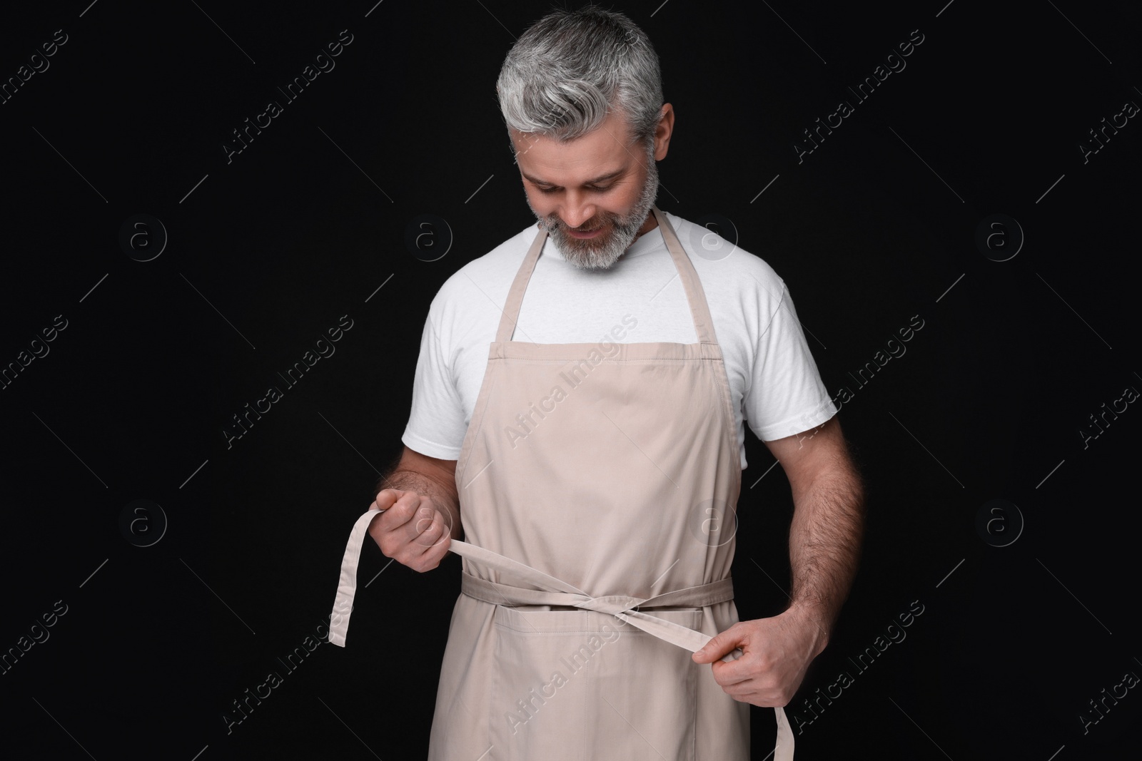 Photo of Man wearing kitchen apron on black background. Mockup for design