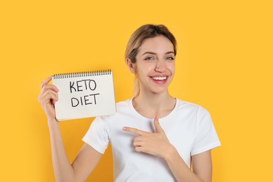 Photo of Woman holding notebook with phrase Keto Diet on yellow background