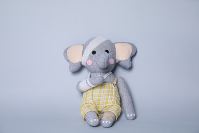 Photo of Toy elephant with bandages on light grey background