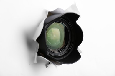 Hidden camera lens through torn hole in white paper