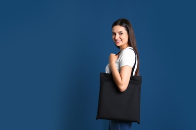 Beautiful young woman with stylish blank eco bag against color background, space for text