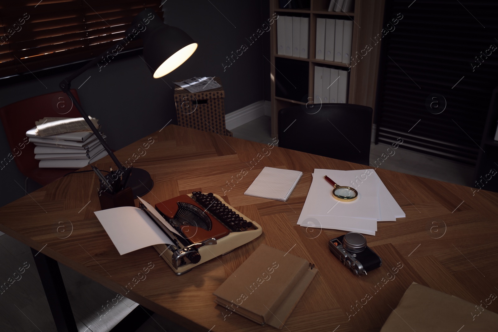 Photo of Photos, papers and typewriter on desk in office. Detective's workplace