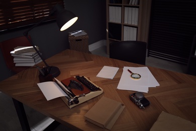 Photo of Photos, papers and typewriter on desk in office. Detective's workplace