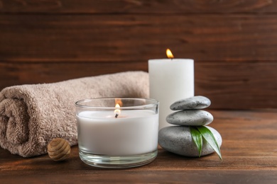 Beautiful composition with spa stones, towel and burning candles on wooden table