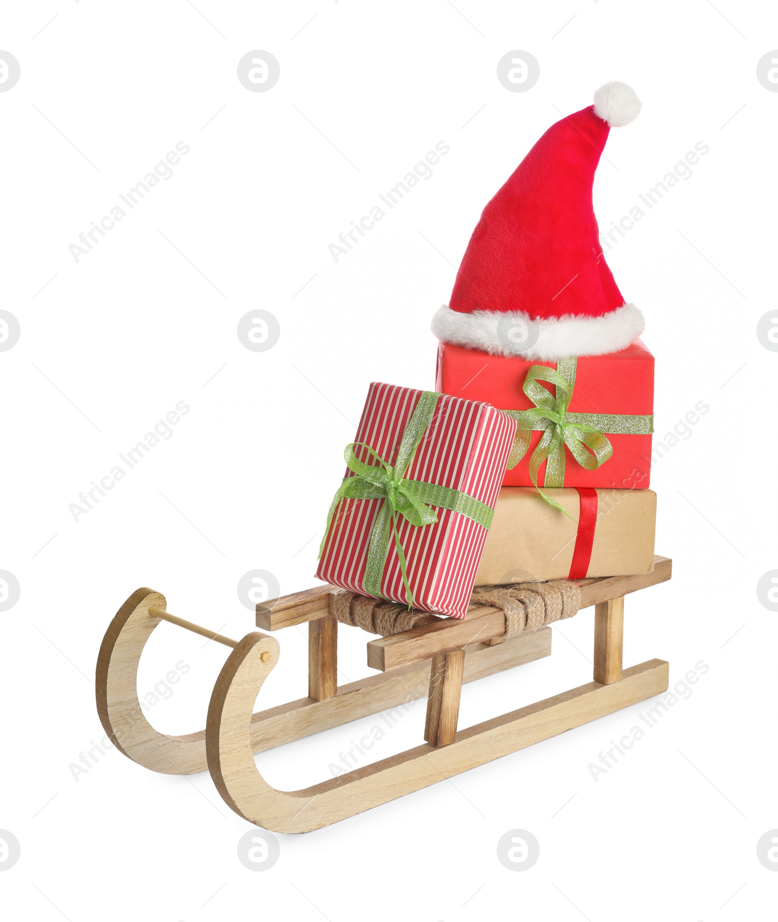 Photo of Wooden sleigh with Christmas gift boxes and Santa hat on white background