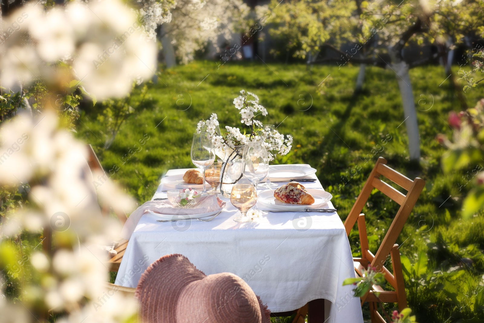 Photo of Beautiful table setting with spring flowers in garden on sunny day