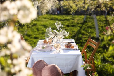 Photo of Beautiful table setting with spring flowers in garden on sunny day