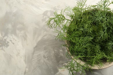 Bowl of fresh green dill on light grey table, top view. Space for text