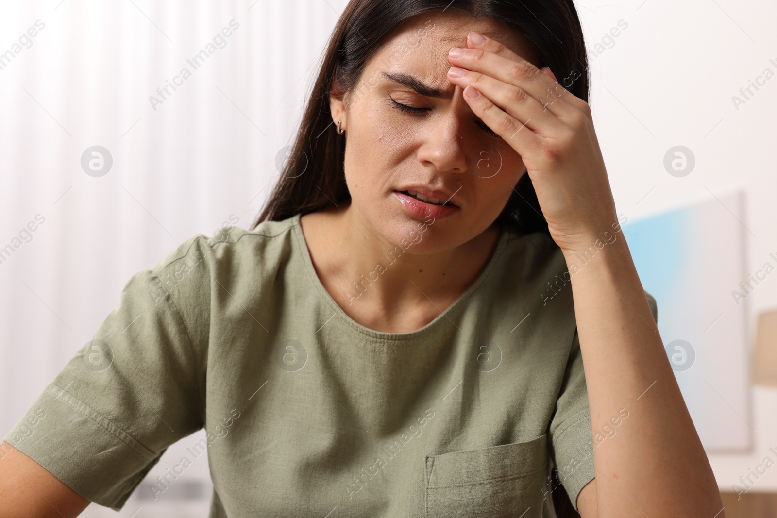 Photo of Sad woman suffering from headache at home