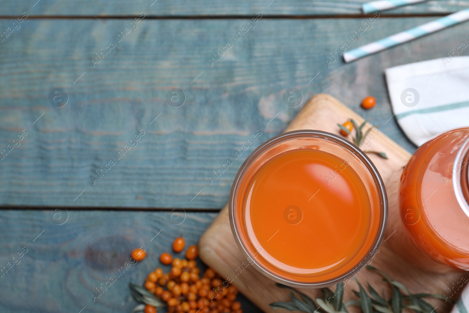 Photo of Delicious sea buckthorn juice on light blue wooden table, top view. Space for text