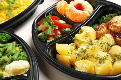 Photo of Lunchboxes with different meals on white table, closeup. Healthy food delivery