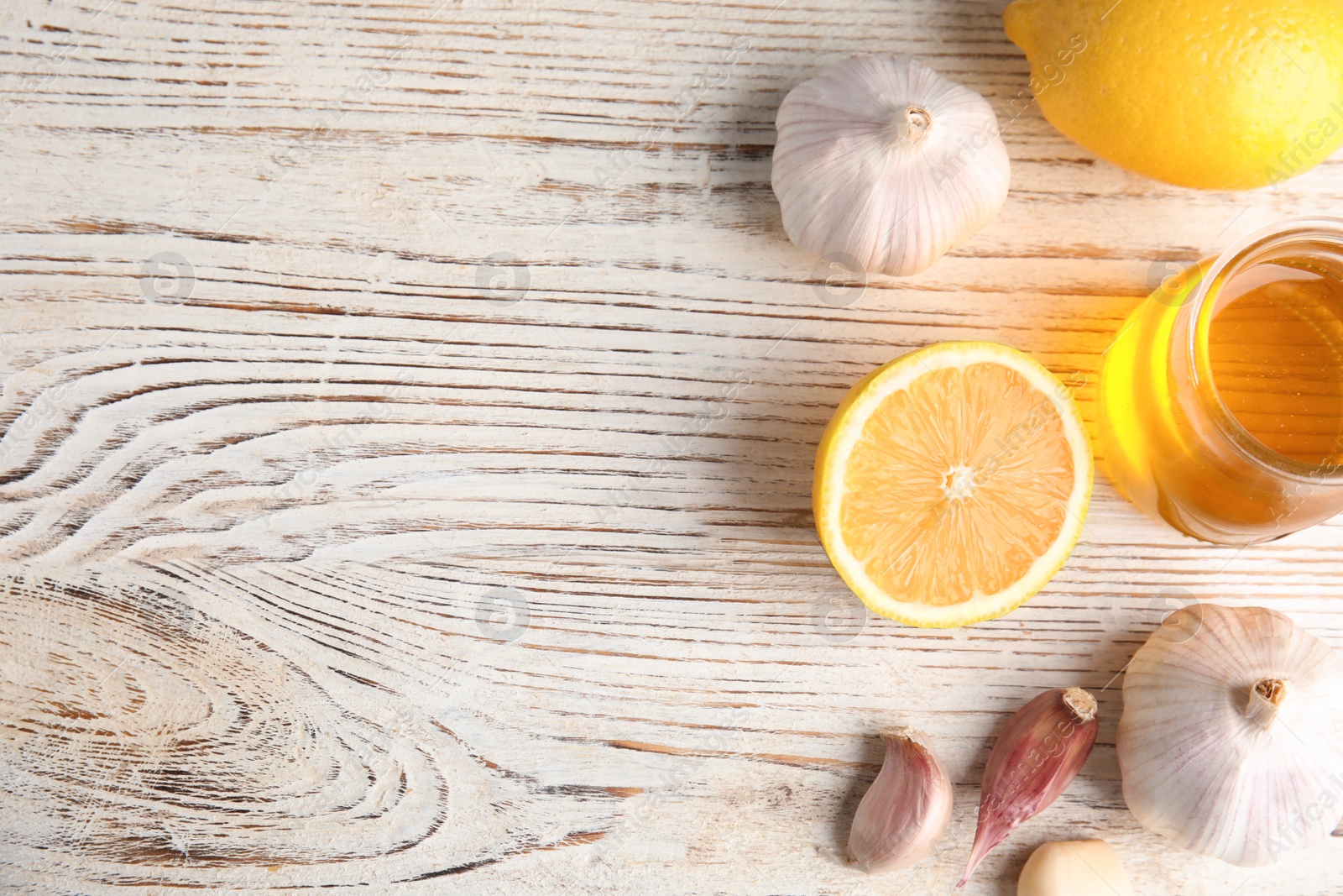 Photo of Flat lay composition with garlic and other cold remedies on white wooden table. Space for text