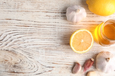 Flat lay composition with garlic and other cold remedies on white wooden table. Space for text