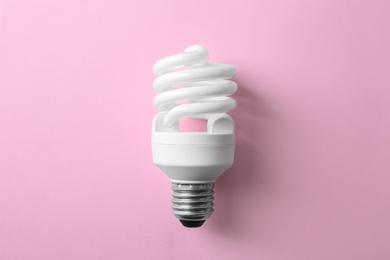Photo of New fluorescent lamp bulb on pink background, top view