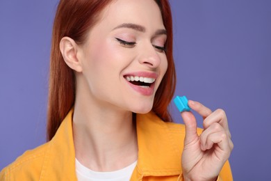 Beautiful woman with bubble gum on purple background